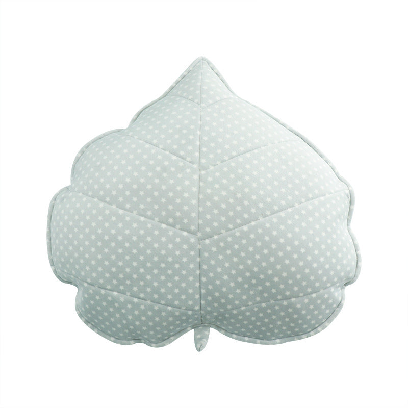 Leaf-shaped cushion with a light green and white polka dot pattern on a white background