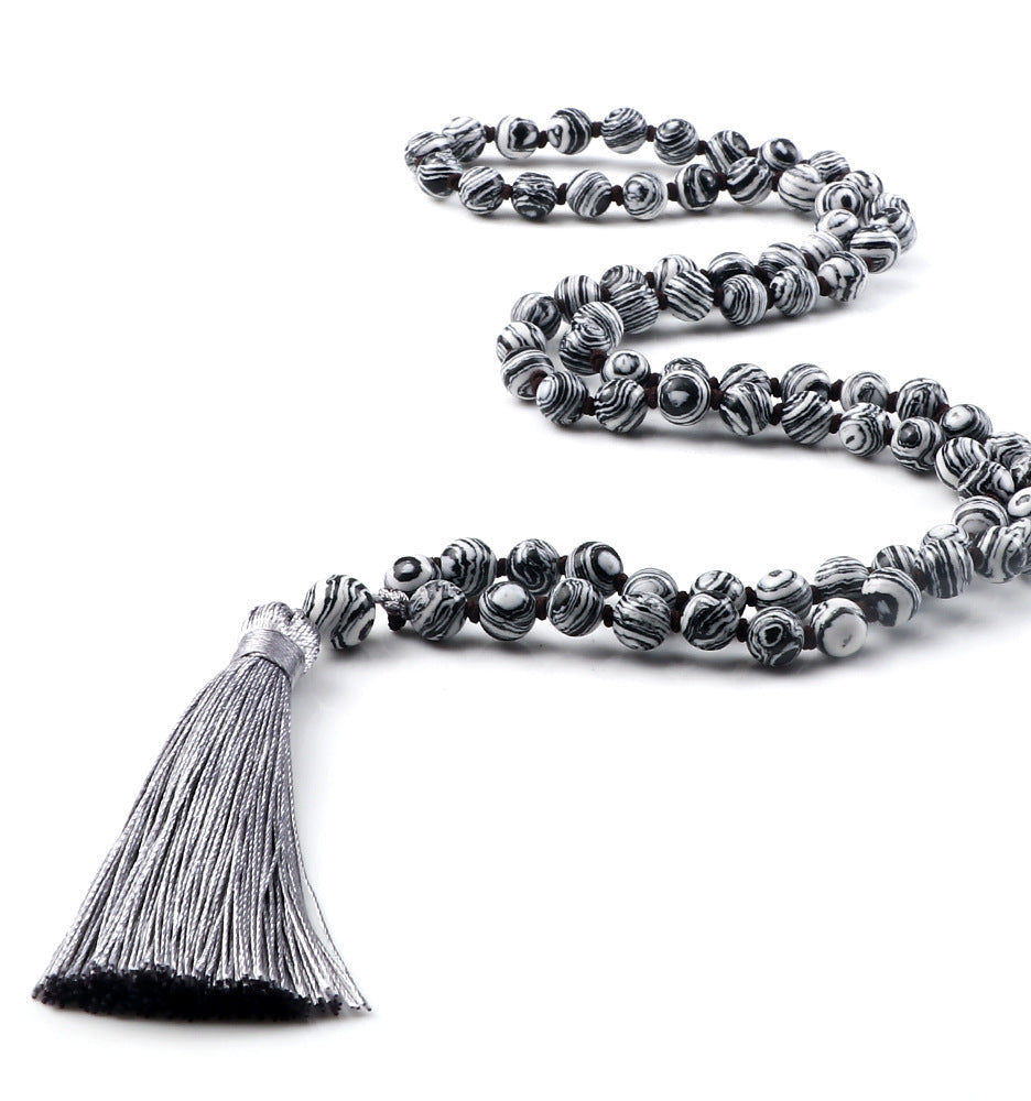 Silver beaded necklace with tassel on a white background