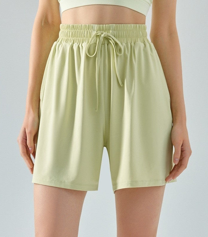 Light green shorts with a drawstring on a plain background