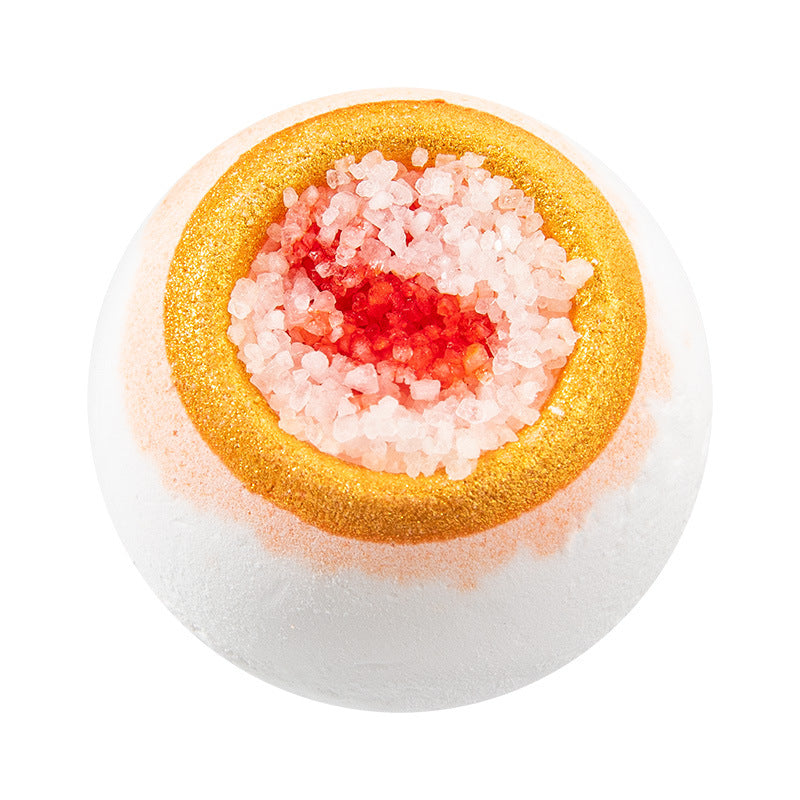Bath bomb with gold, pink, and red layers on a white background
