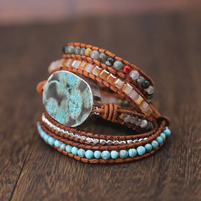 Multistrand bracelet with beads and a large stone on a wooden surface