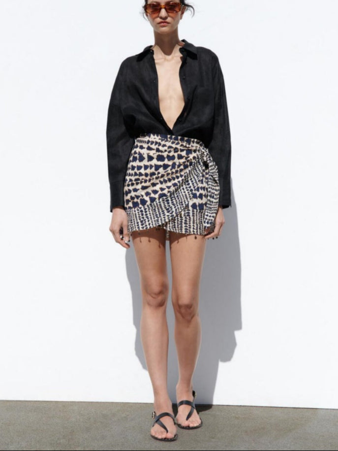 Woman wearing a black top and leopard print skirt on a white background
