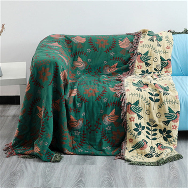 Two patterned blankets draped over a couch in a room setting.