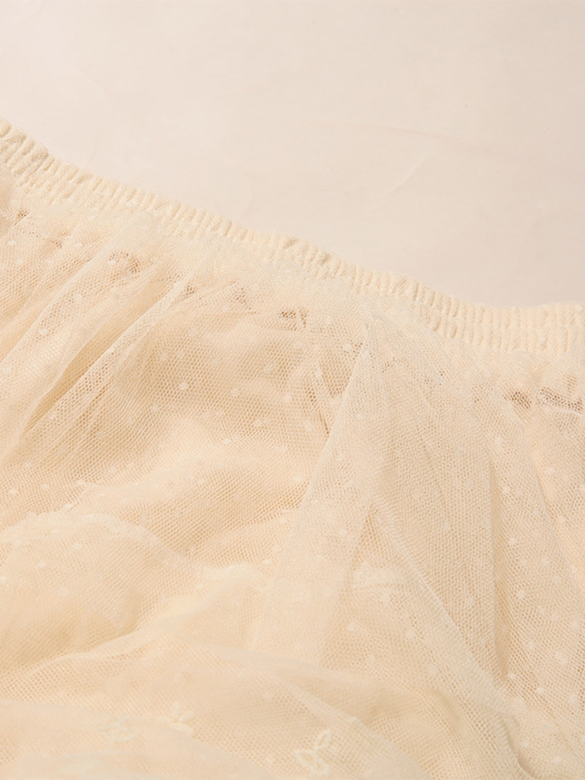 Close-up of beige tulle fabric with a soft texture.