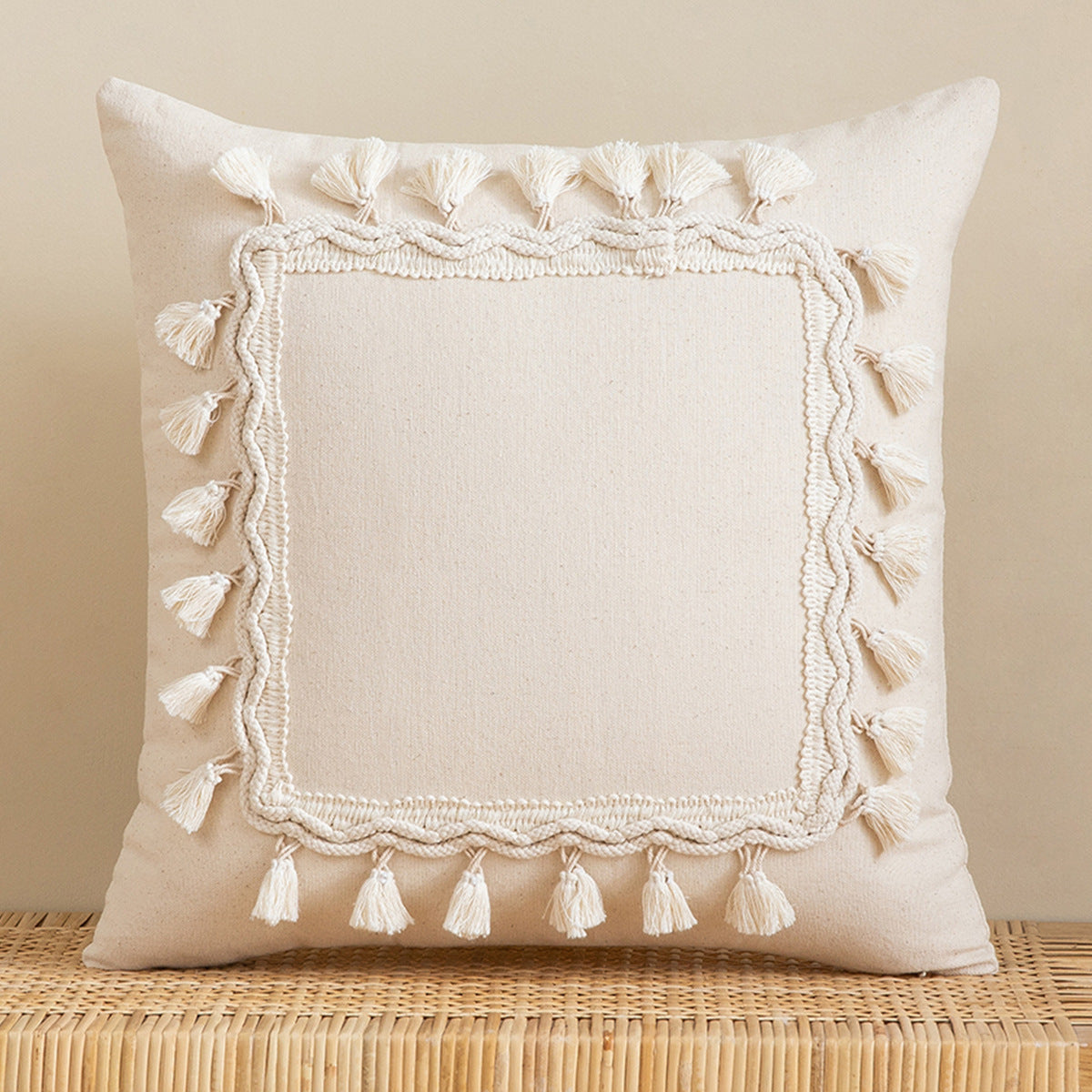 Beige pillow with tassel trim on a beige background