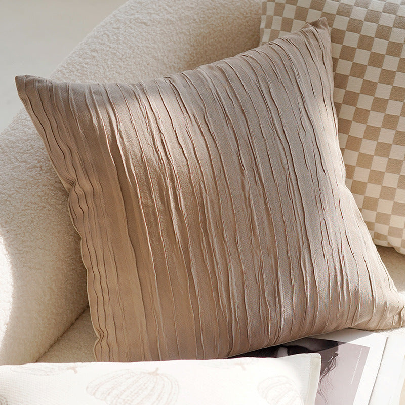 Beige textured pillow on a sofa with a checkered pattern in the background