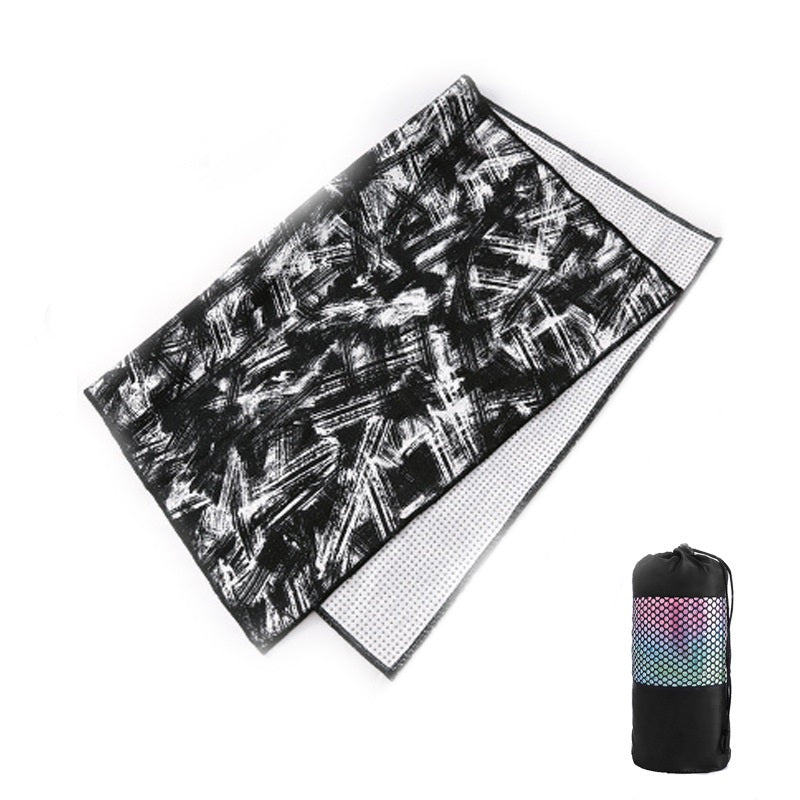 Black and white patterned towel with a mesh backing and rolled-up black bag on a white background