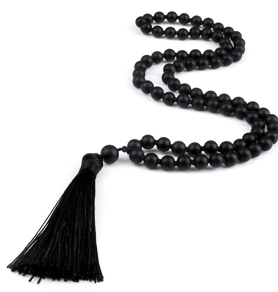 Black beaded necklace with a tassel on a white background