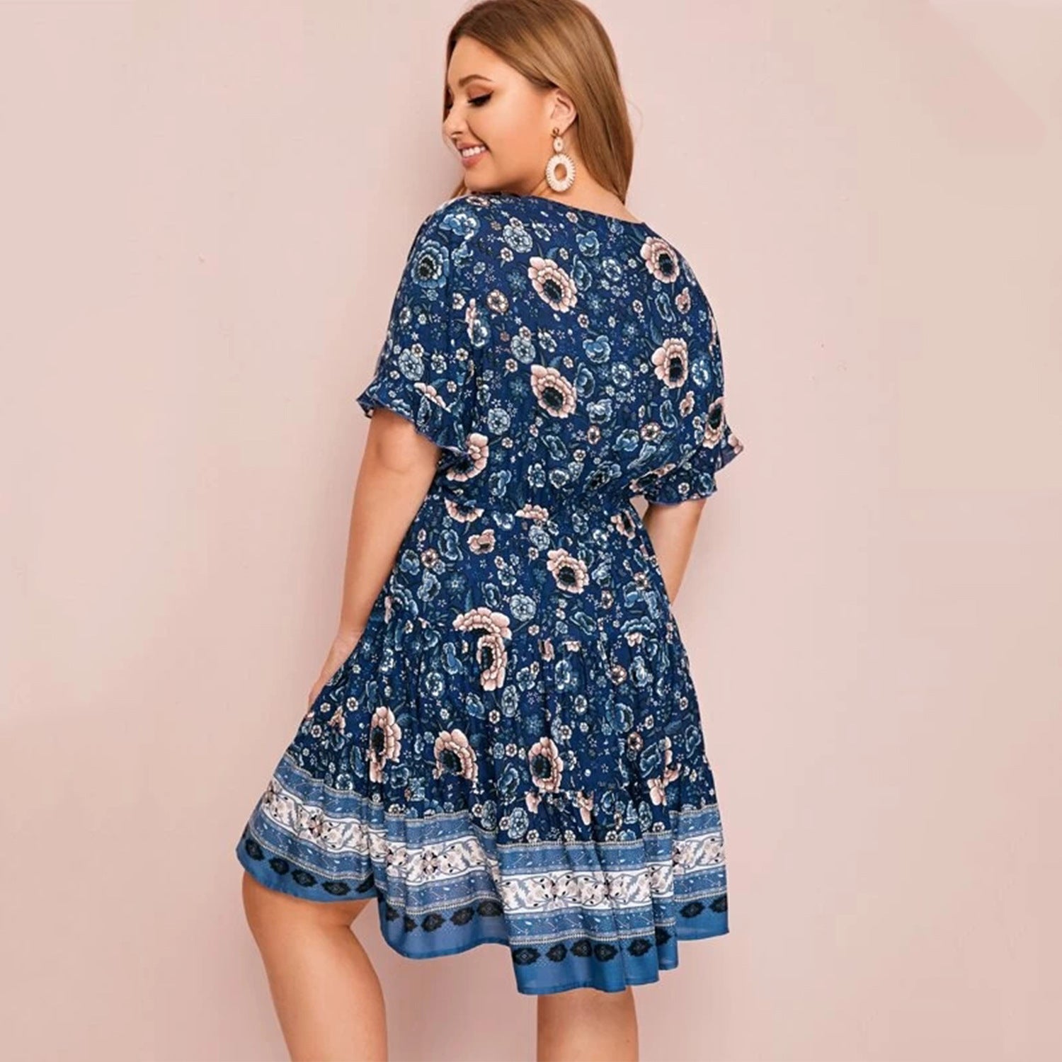 Woman wearing a blue floral dress against a pink background
