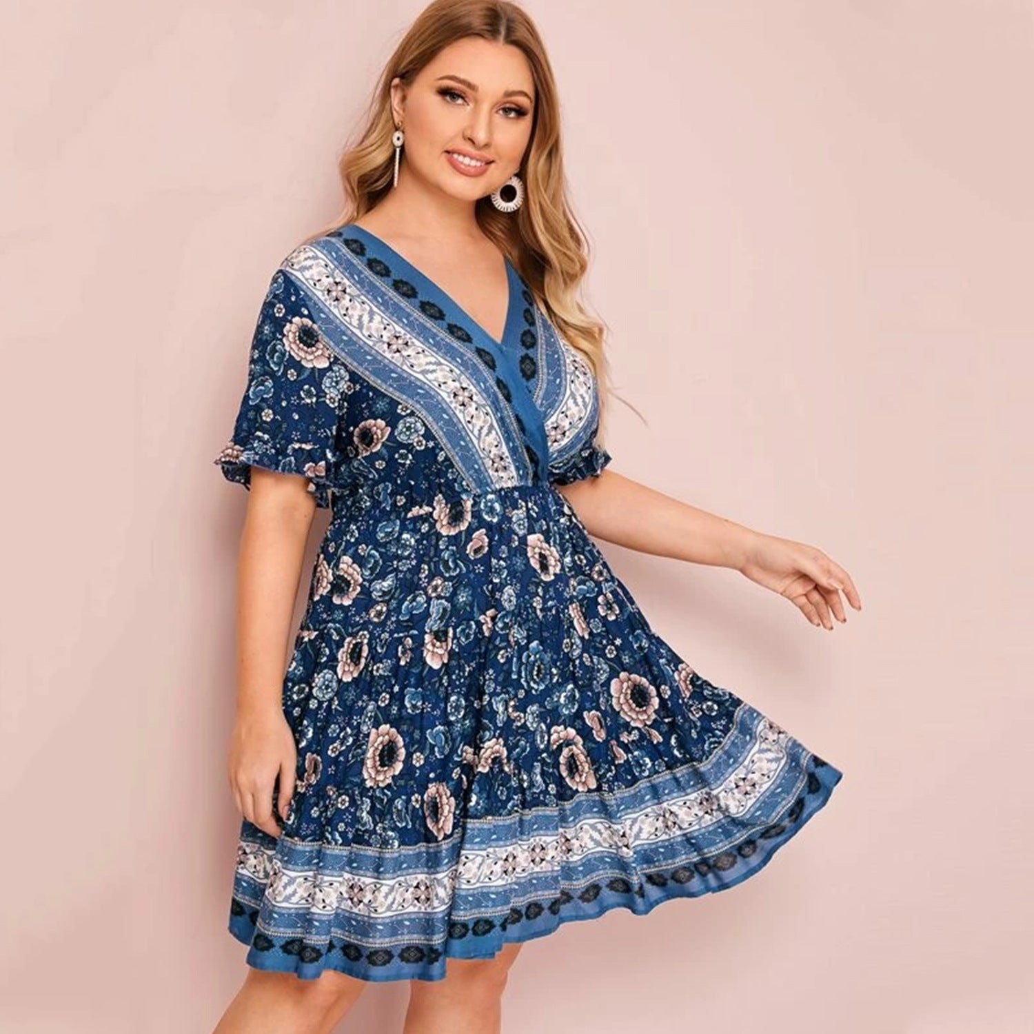 Woman wearing a blue patterned dress against a pink background