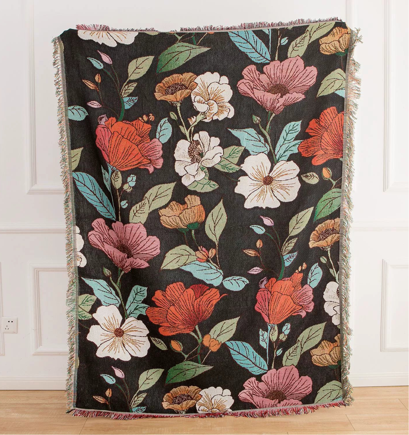 Floral-patterned throw blanket on a wooden floor with a white wall background