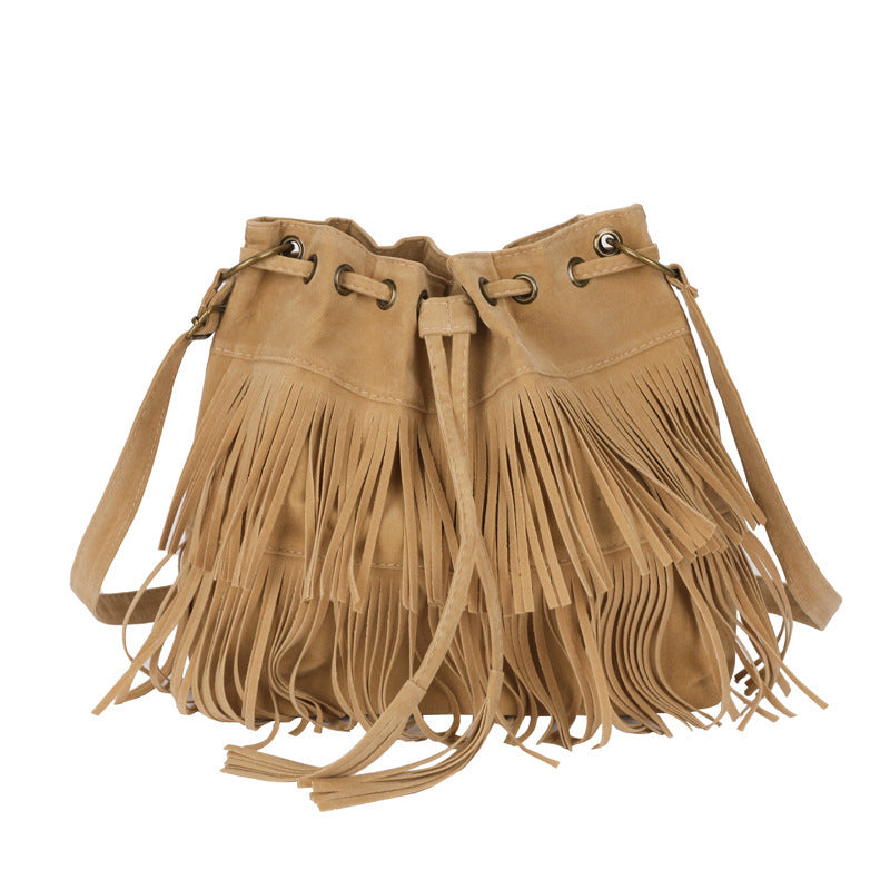 Tan suede handbag with fringe details on a white background