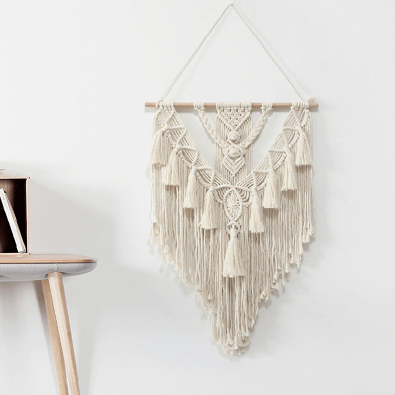 Macrame wall hanging on a white wall with a shelf in the corner.