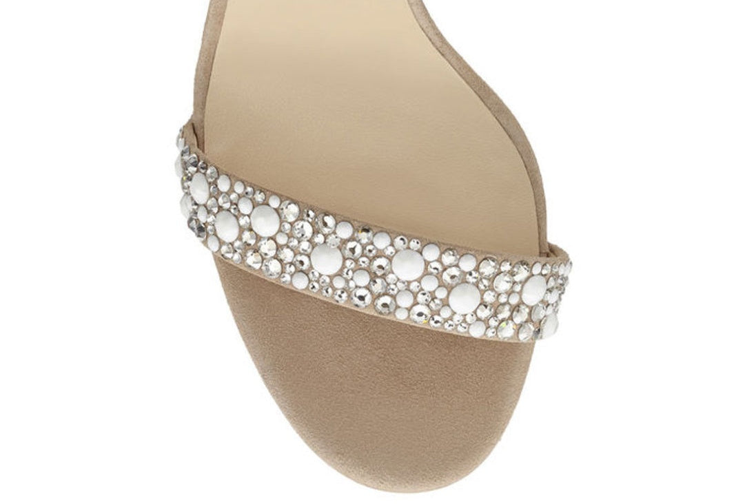 Beige sandal with a decorative silver band on a white background