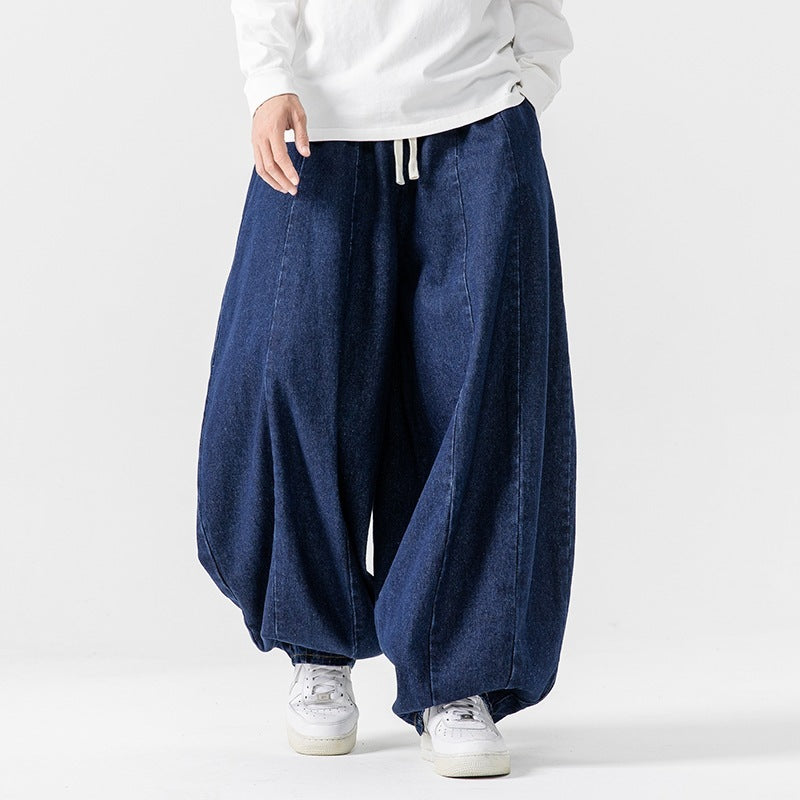 Person wearing blue wide-leg jeans and white sneakers on a plain background