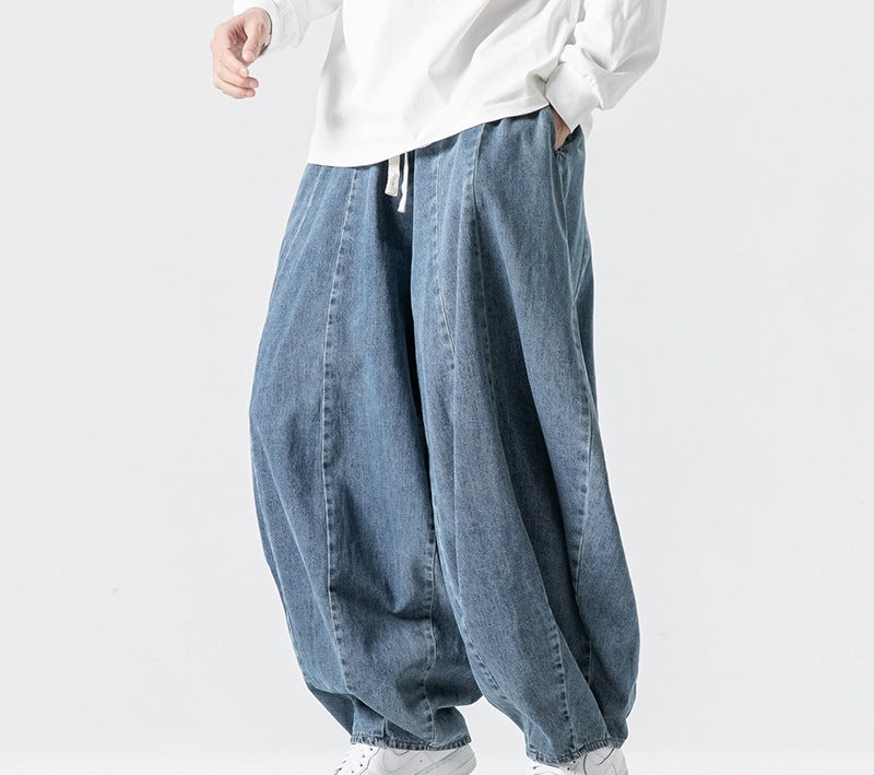Person wearing light blue denim baggy pants and white sneakers on a white background