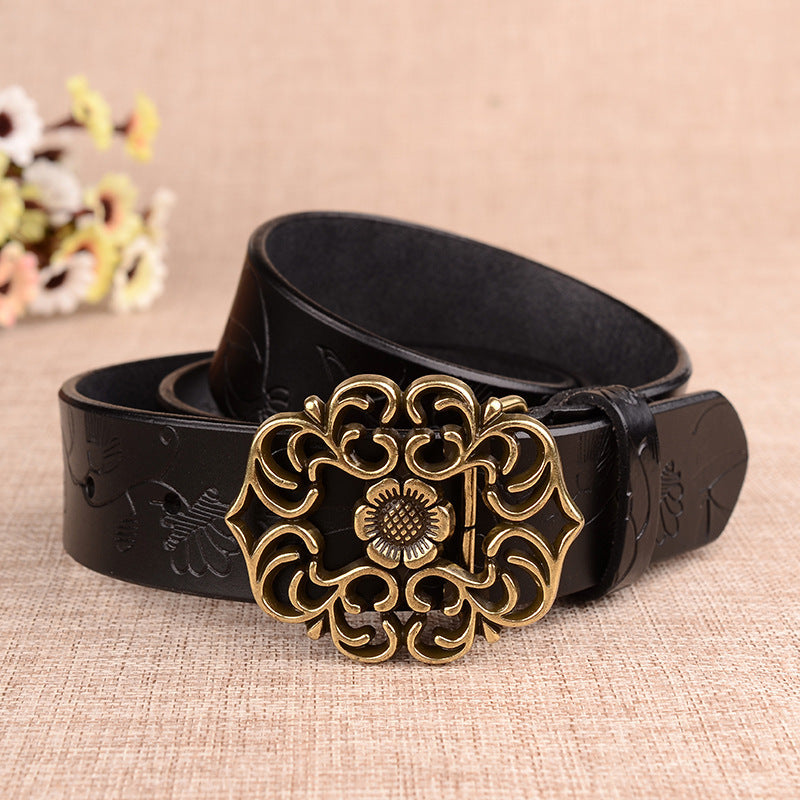 Black leather belt with a decorative gold buckle on a beige fabric background