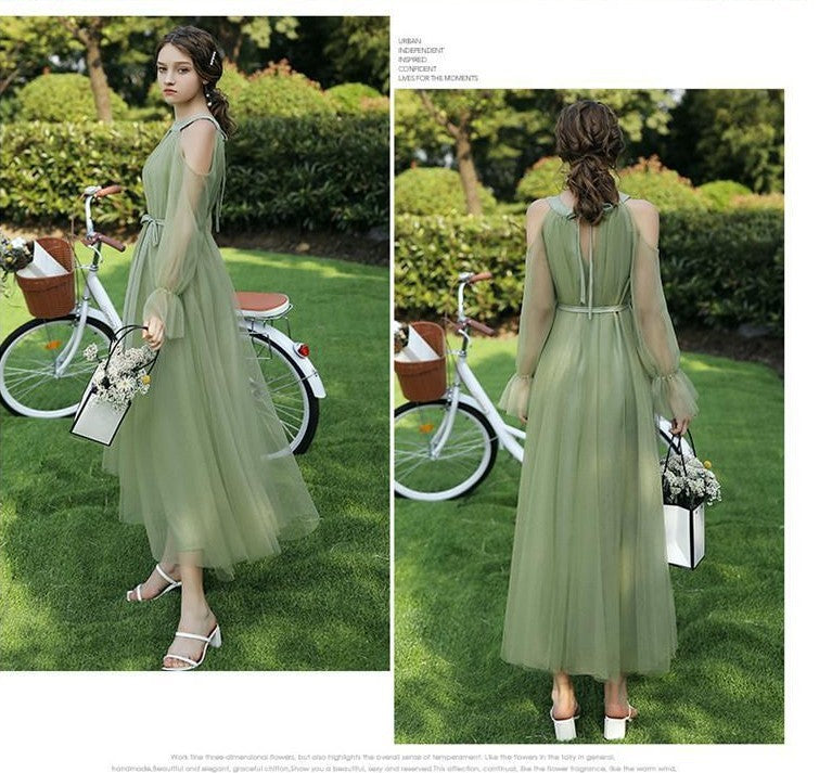 Woman in a green dress standing next to a bicycle in a park setting