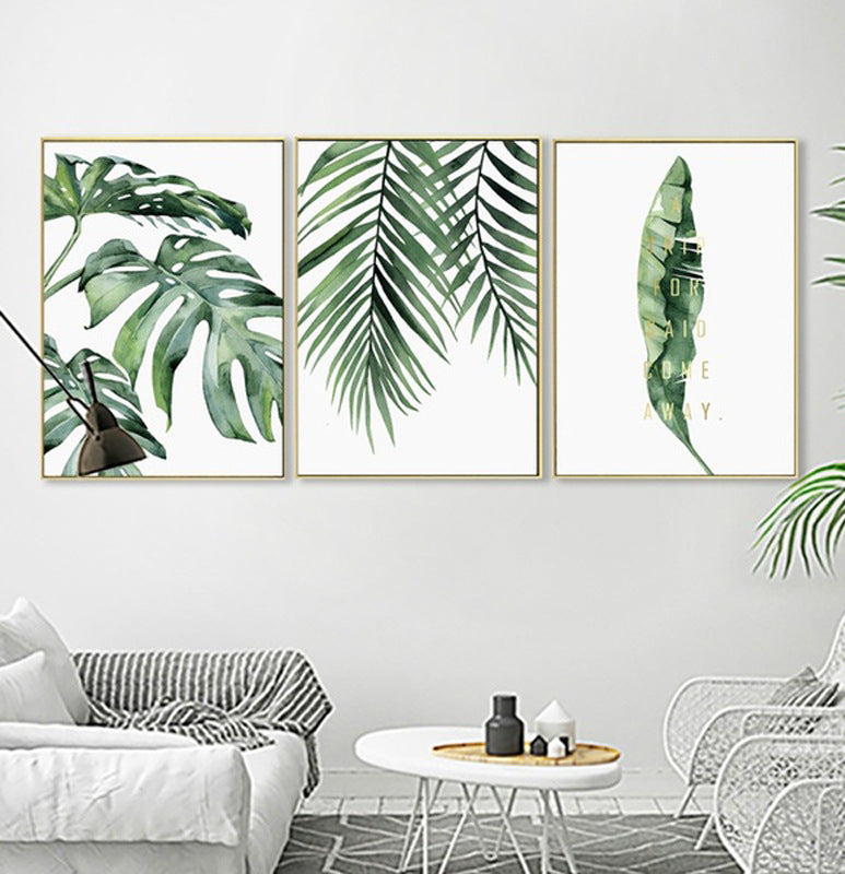 Three framed botanical prints of green leaves in a living room setting.