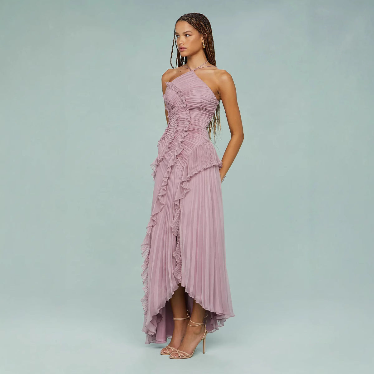 Woman wearing a pink one-shoulder dress with ruffles on a light gray background