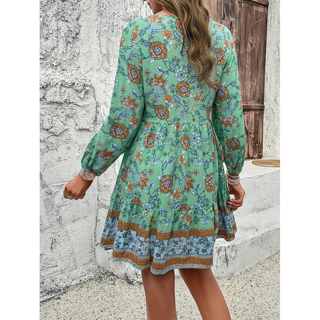 Woman wearing a green floral dress standing against a stone wall.