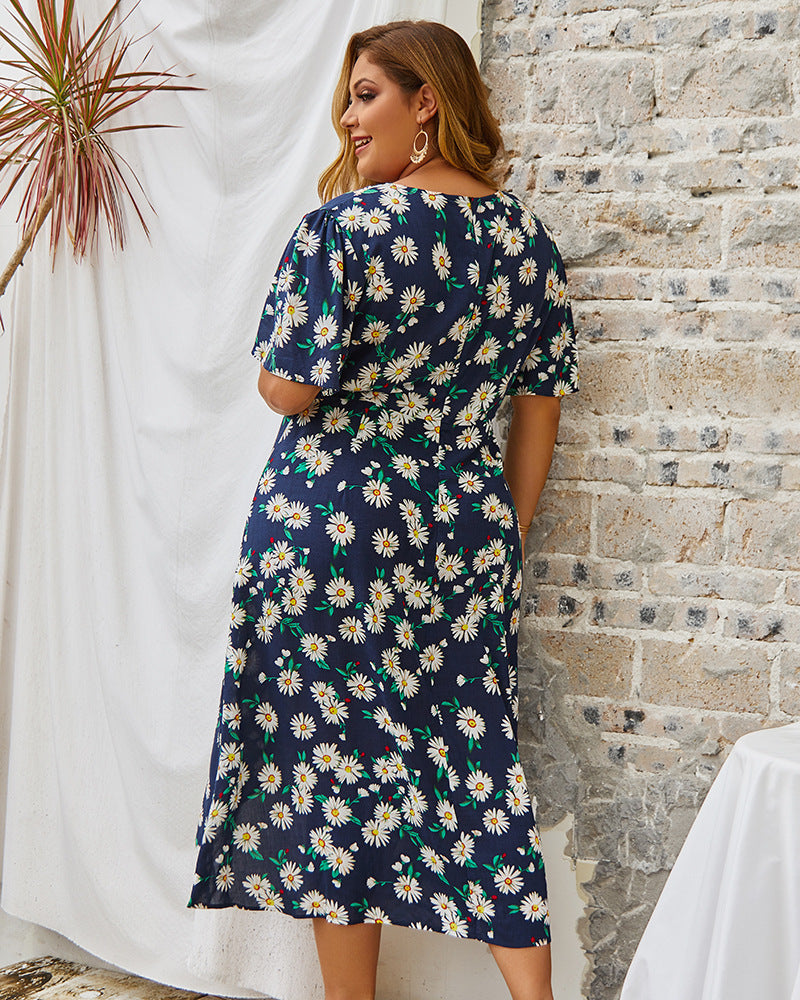Woman wearing a navy floral dress against a stone wall.