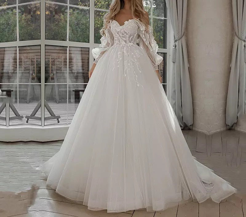 White wedding dress with lace details in a room with large windows.