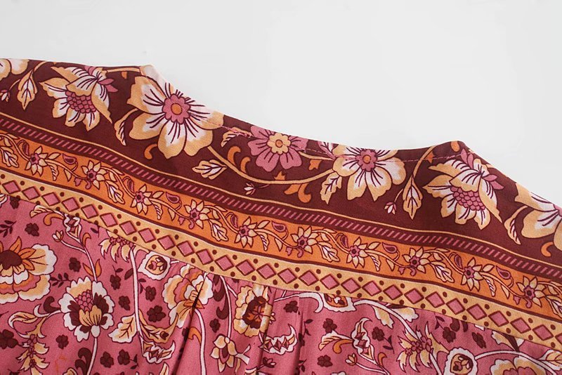 Close-up of a fabric with floral and geometric patterns in pink, orange, and brown on a white background.