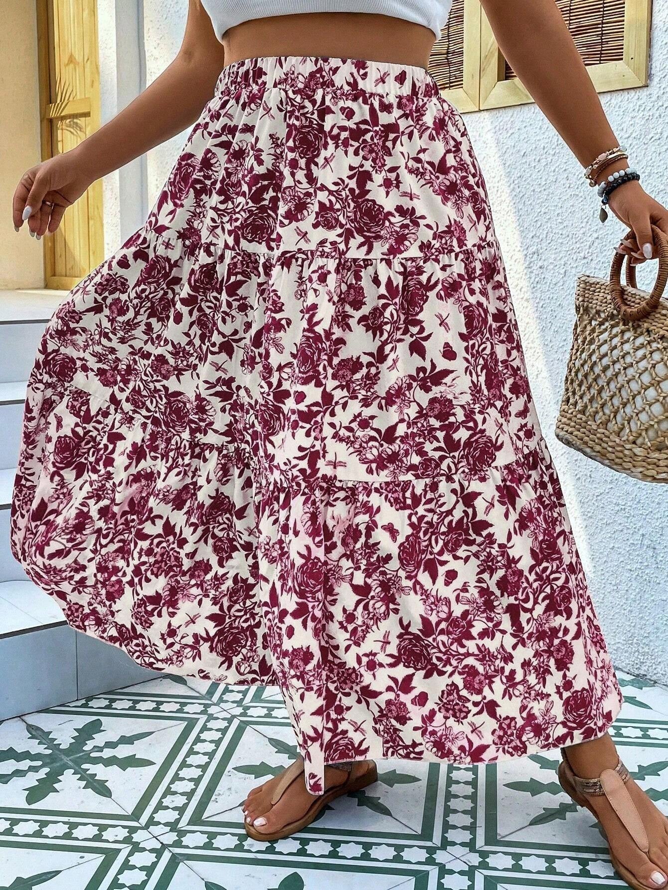 Person wearing a floral skirt with a white top and sandals, holding a straw bag on a tiled floor.
