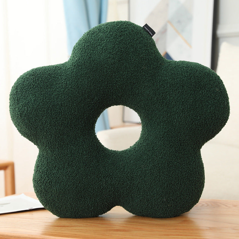 Flower-shaped green cushion on a wooden surface with a blurred background