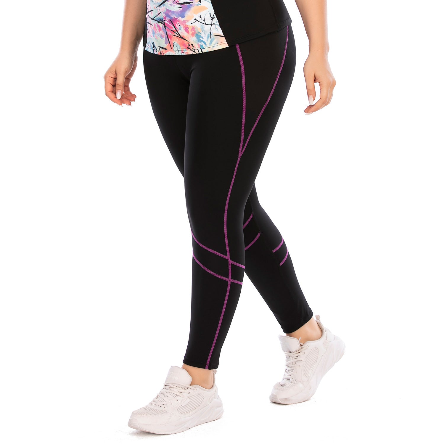 Person wearing black leggings with pink lines and white sneakers on a white background
