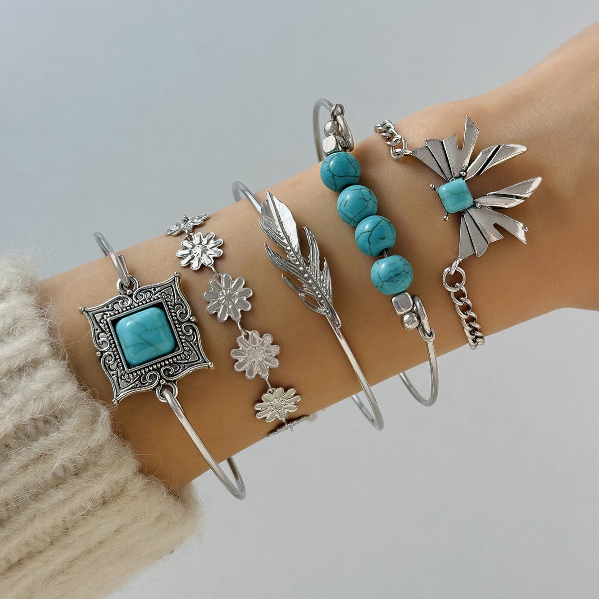 Silver and turquoise jewelry set on a wrist against a neutral background