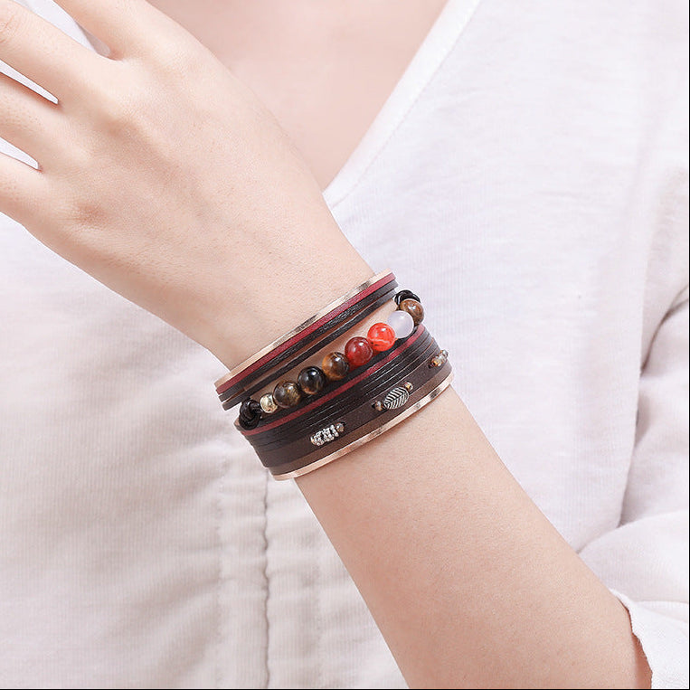 Close-up of a person wearing multiple bracelets on a plain background