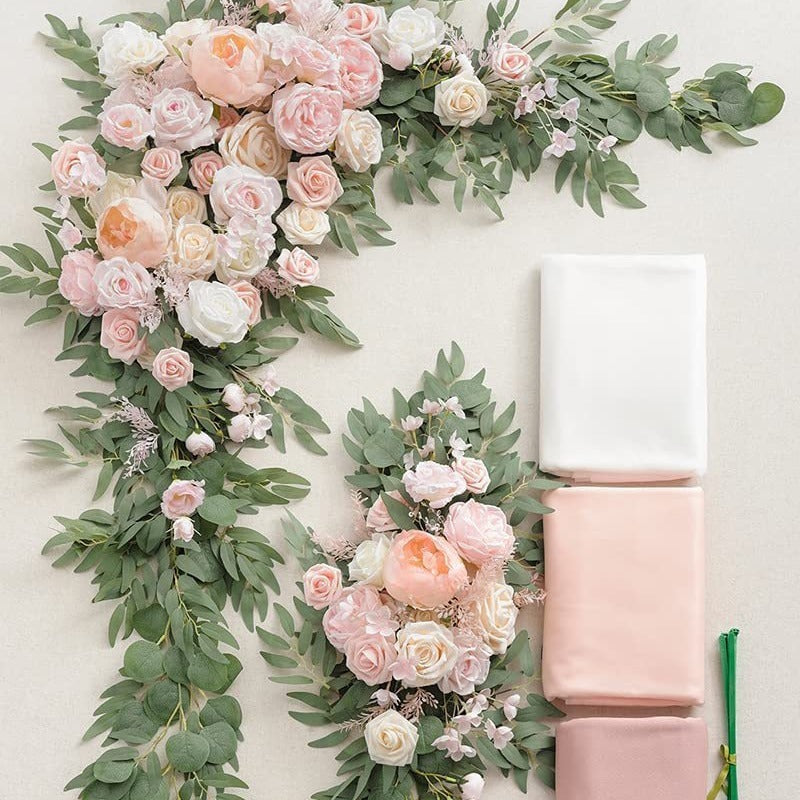 Decorative floral arrangement with pink and white flowers and green leaves on a light background.