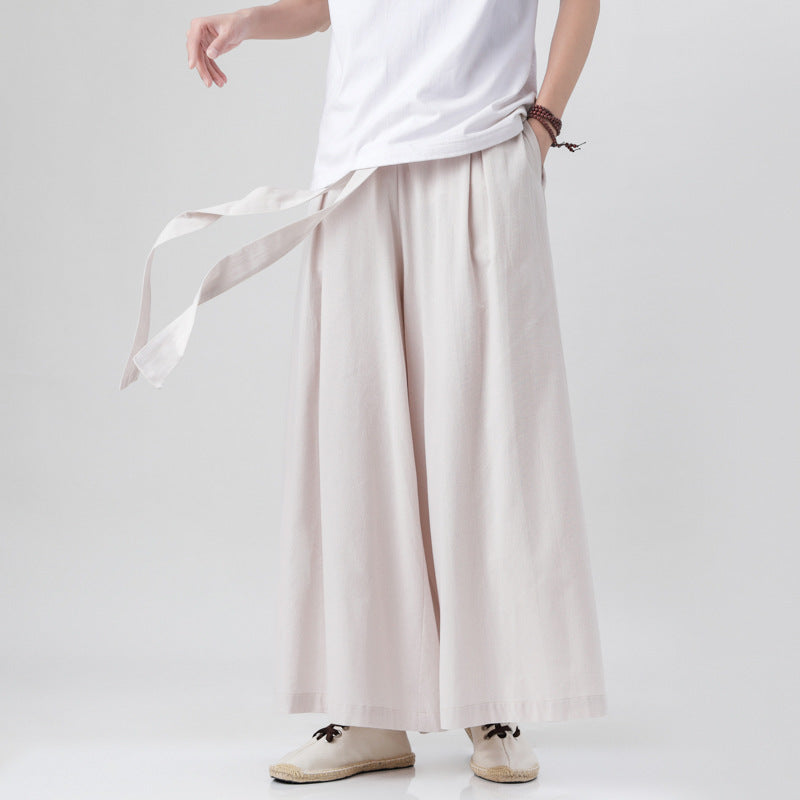 Person wearing light-colored wide-leg pants with a white top on a plain background