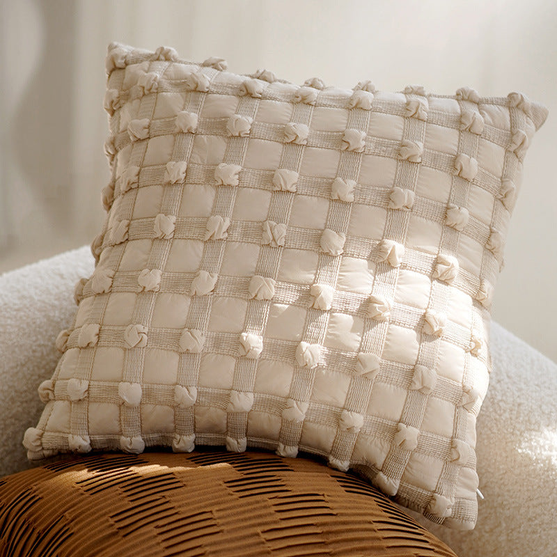 Textured beige pillow on a chair with a neutral background