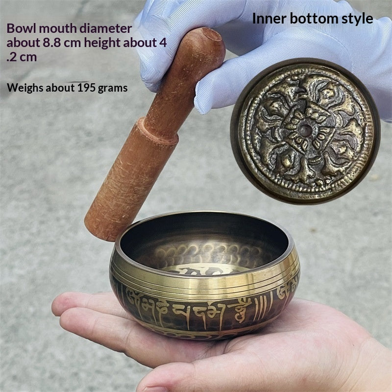 Brass singing bowl with wooden striker held by a hand, showing details and specifications.