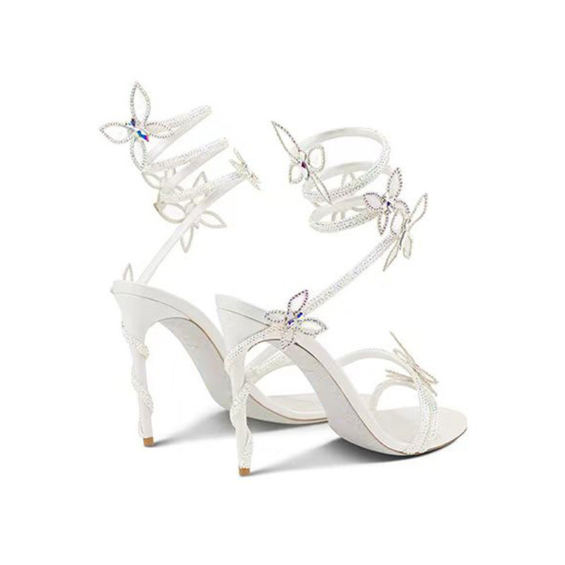 White high-heeled sandals with butterfly designs on a white background