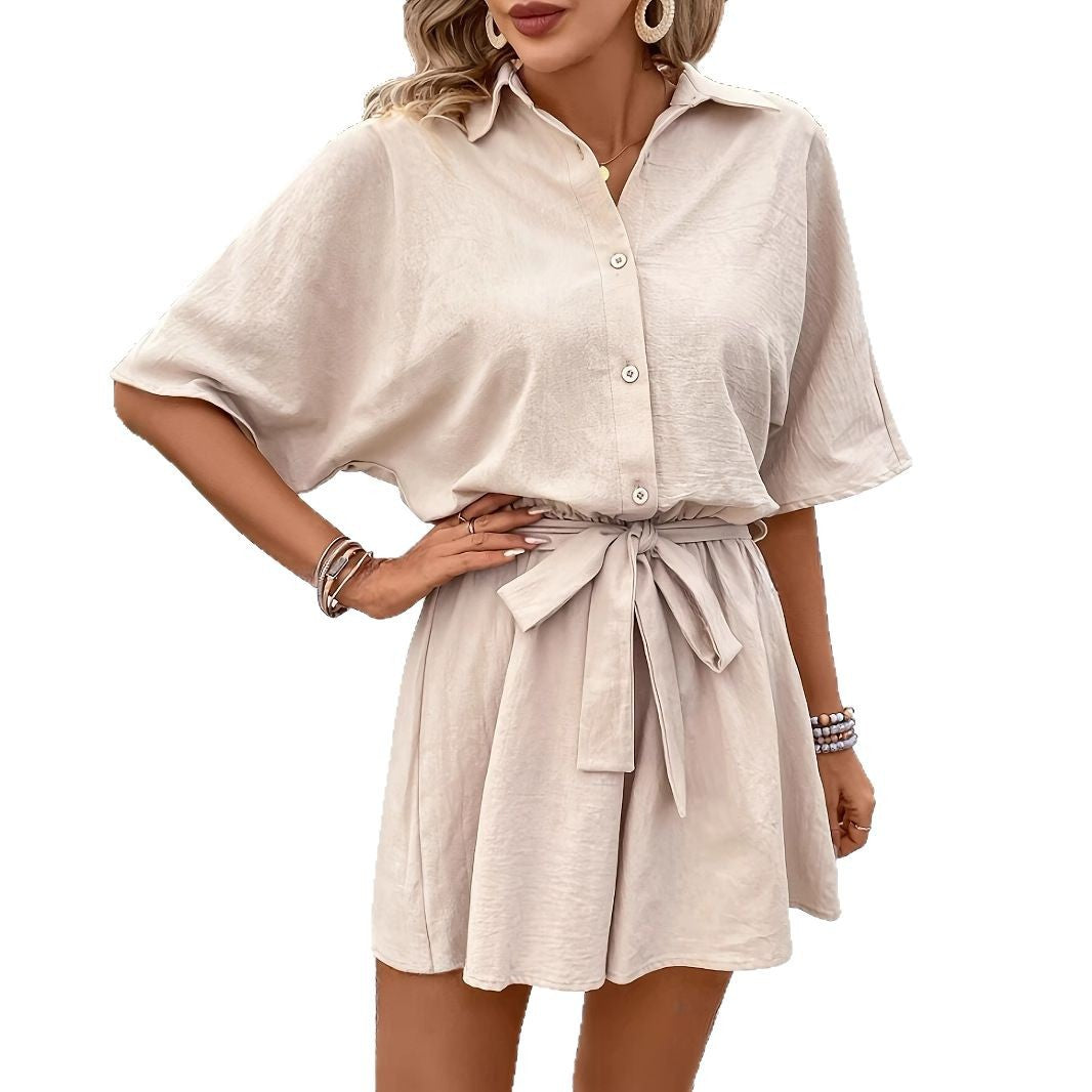 Woman wearing a beige button-up dress with a belt on a white background
