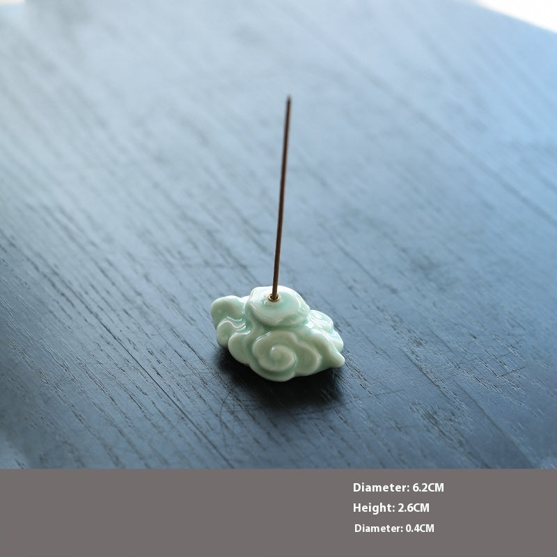 Celadon auspicious cloud incense holder with an incense stick on a dark wooden surface