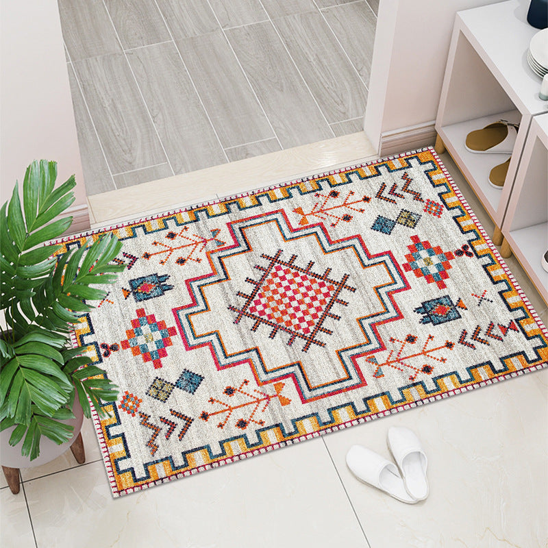 Decorative rug with geometric pattern on a tiled floor, next to a plant and white slippers.