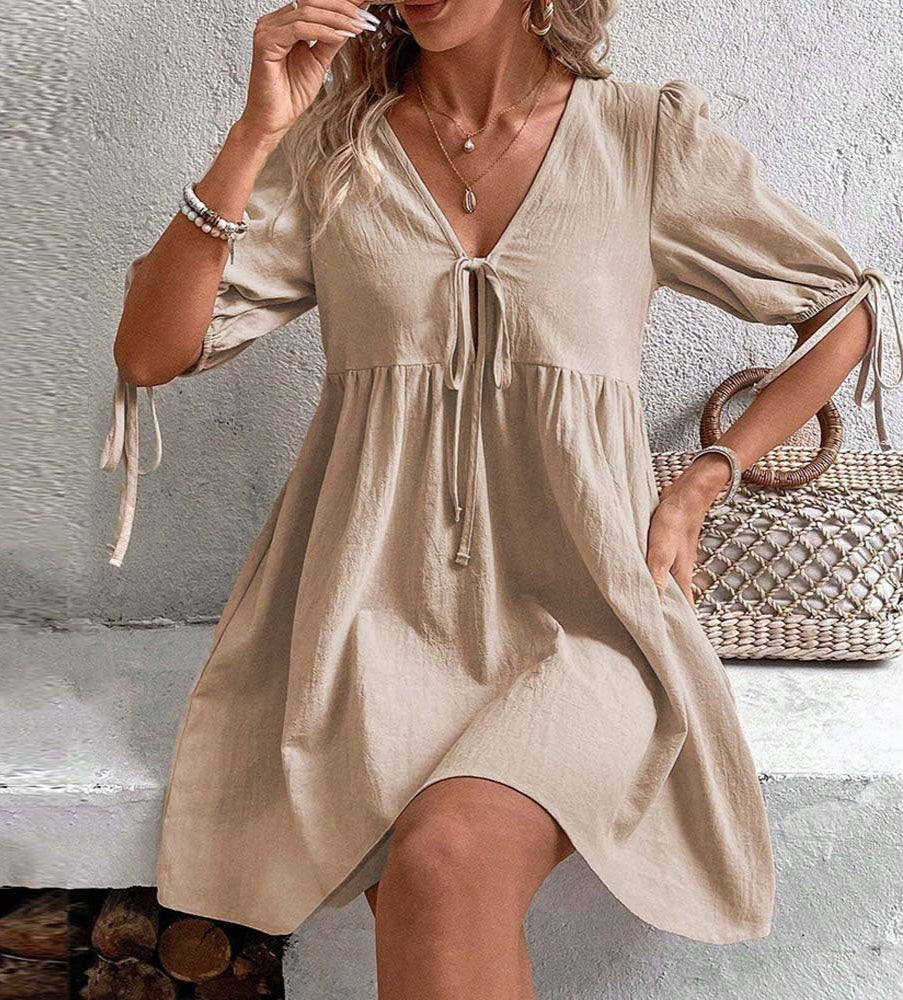 Woman wearing a beige dress with a textured wall background