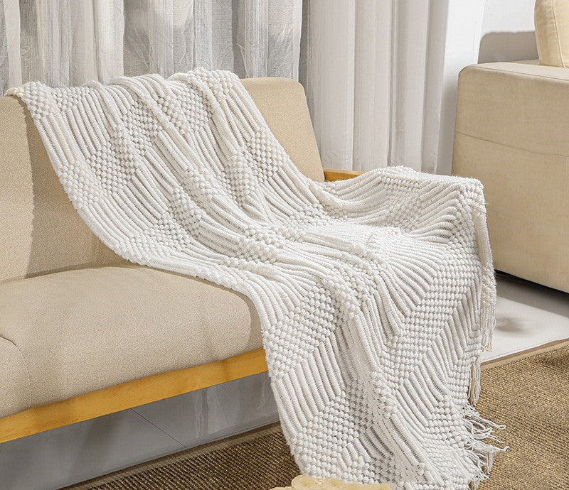 White textured throw blanket draped over a beige sofa in a living room setting.