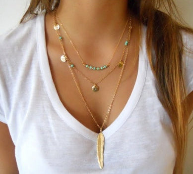 Layered gold necklaces on a white shirt