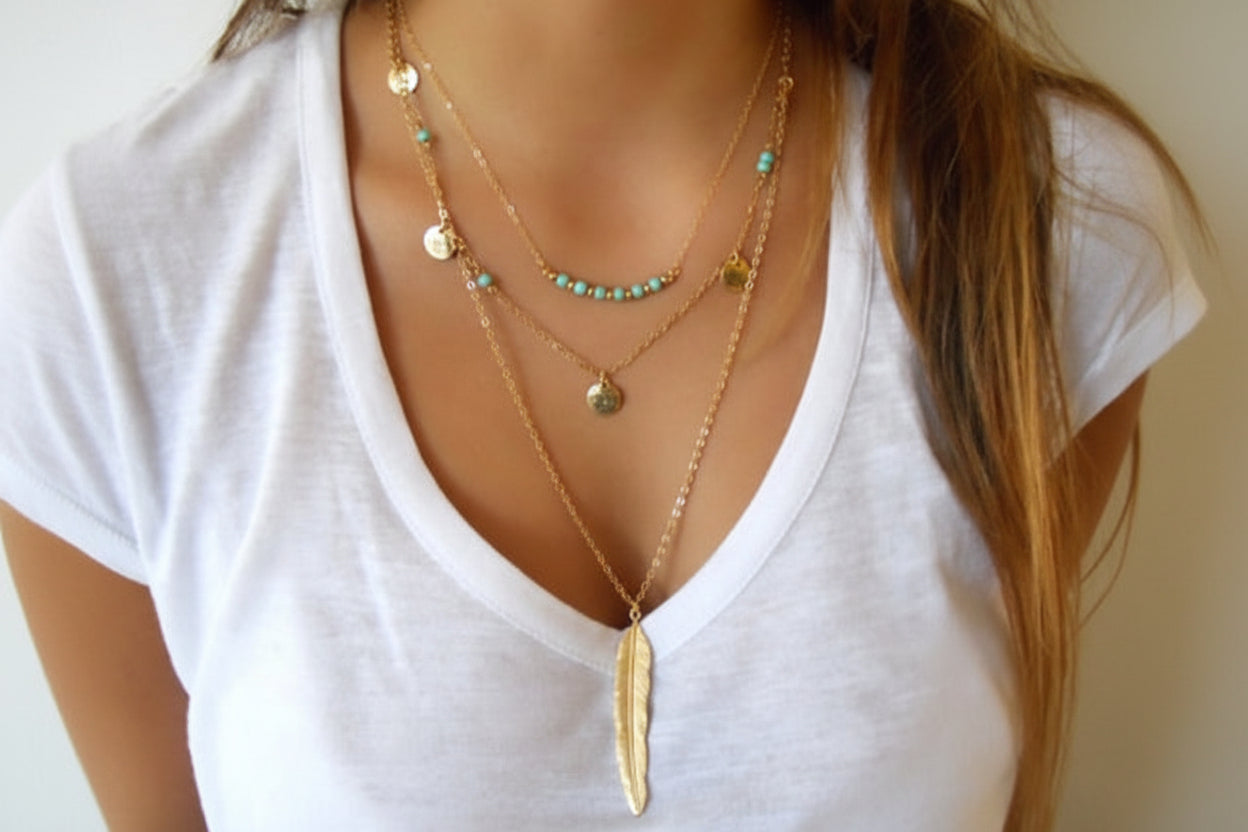 Layered gold necklaces on a white shirt