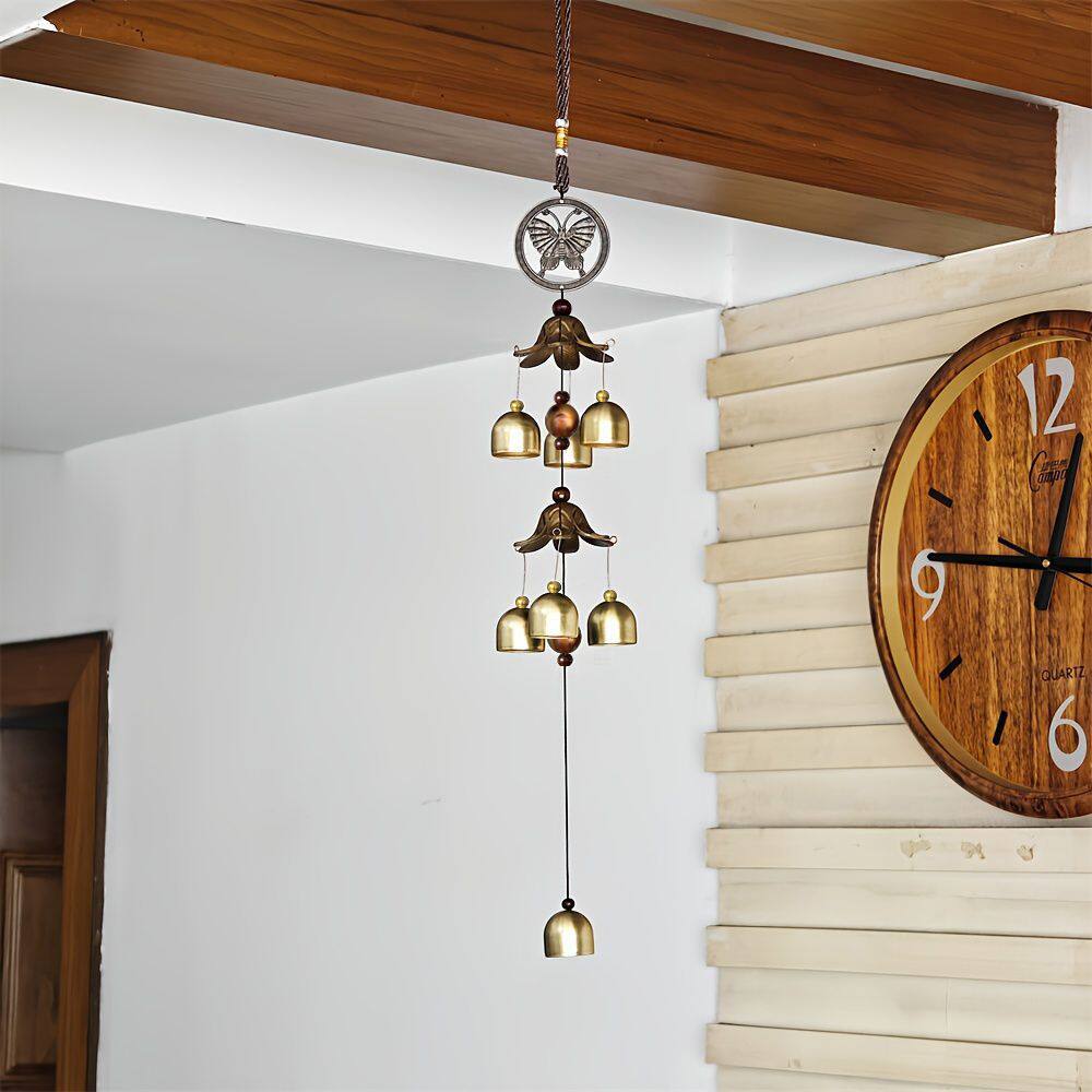 Decorative hanging bell chime with wooden wall clock in the background