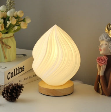 Decorative lamp on a shelf with books, flowers, and a figurine.