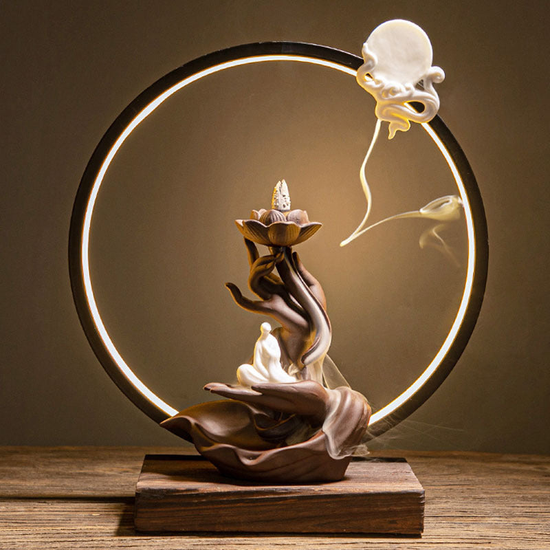 Decorative lamp with a circular light fixture, hand holding a lotus flower, and a small figure on a wooden base.