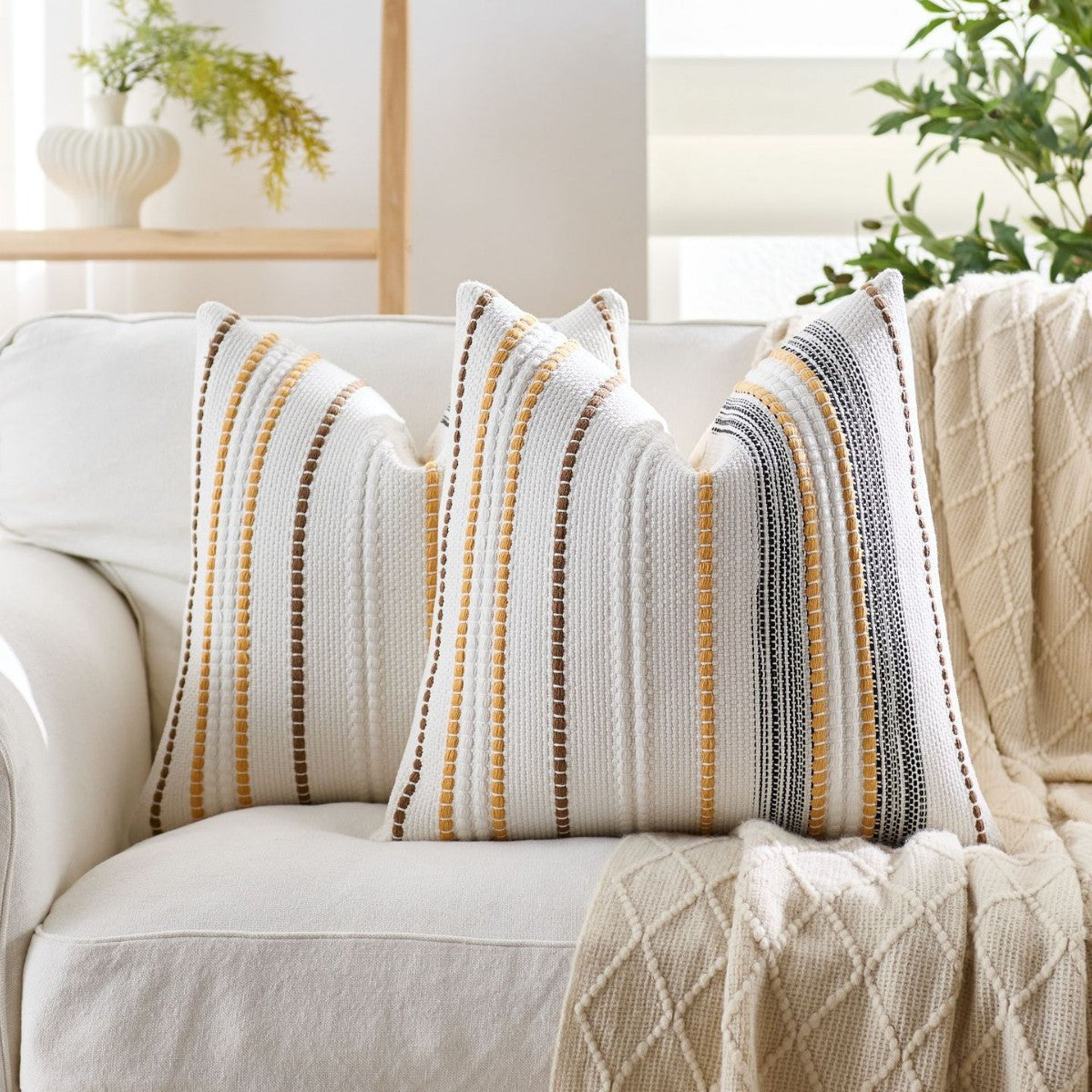 Decorative pillows with striped patterns on a white sofa in a bright living room.