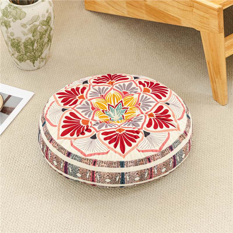 Decorative round cushion with floral pattern on a beige floor.